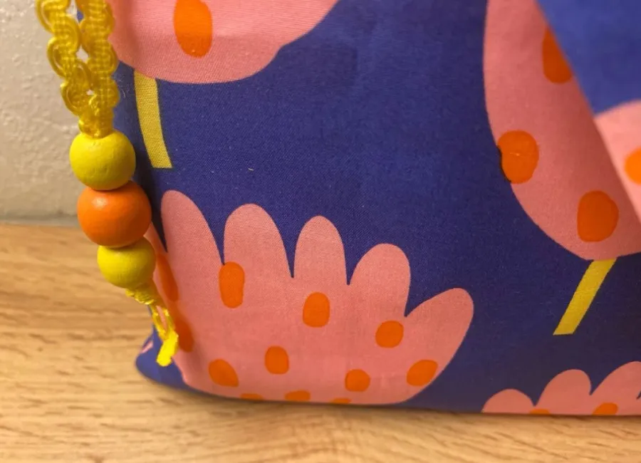 Gros plan du tissu bleu violet à grands motifs floraux roses et oranges de la pochette liseuse cousue main Créa'Flo
