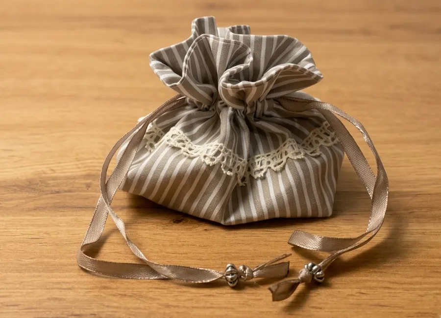 Pochette en tissu rayé beige fermée avec ruban, pour ranger poupées tracas Créa'Flo