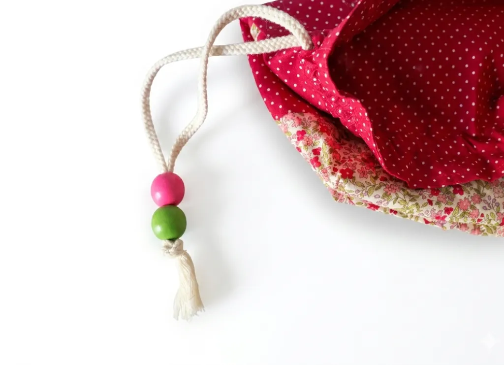 Pochon rouge fleuri zoom détail cordon, perles rose et vert anis enfilées main, tissu fleuri, Créa'Flo